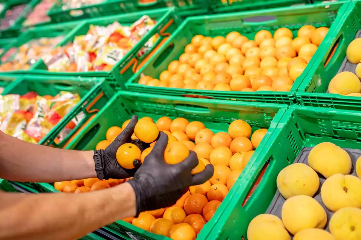 Fotografía de un empleado cogiendo mandarinas de Mercadona