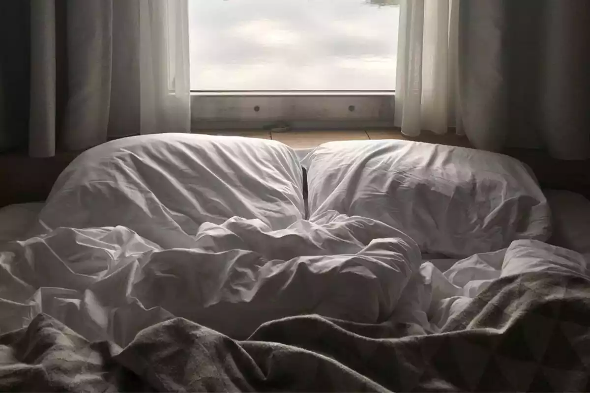 Imagen de una cama con las sábanas revueltas