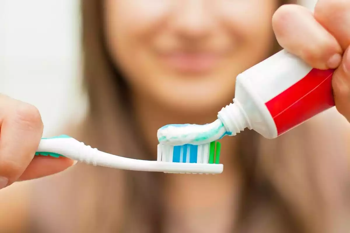 Una mujer poniendo pasta de dientes en su cepillo