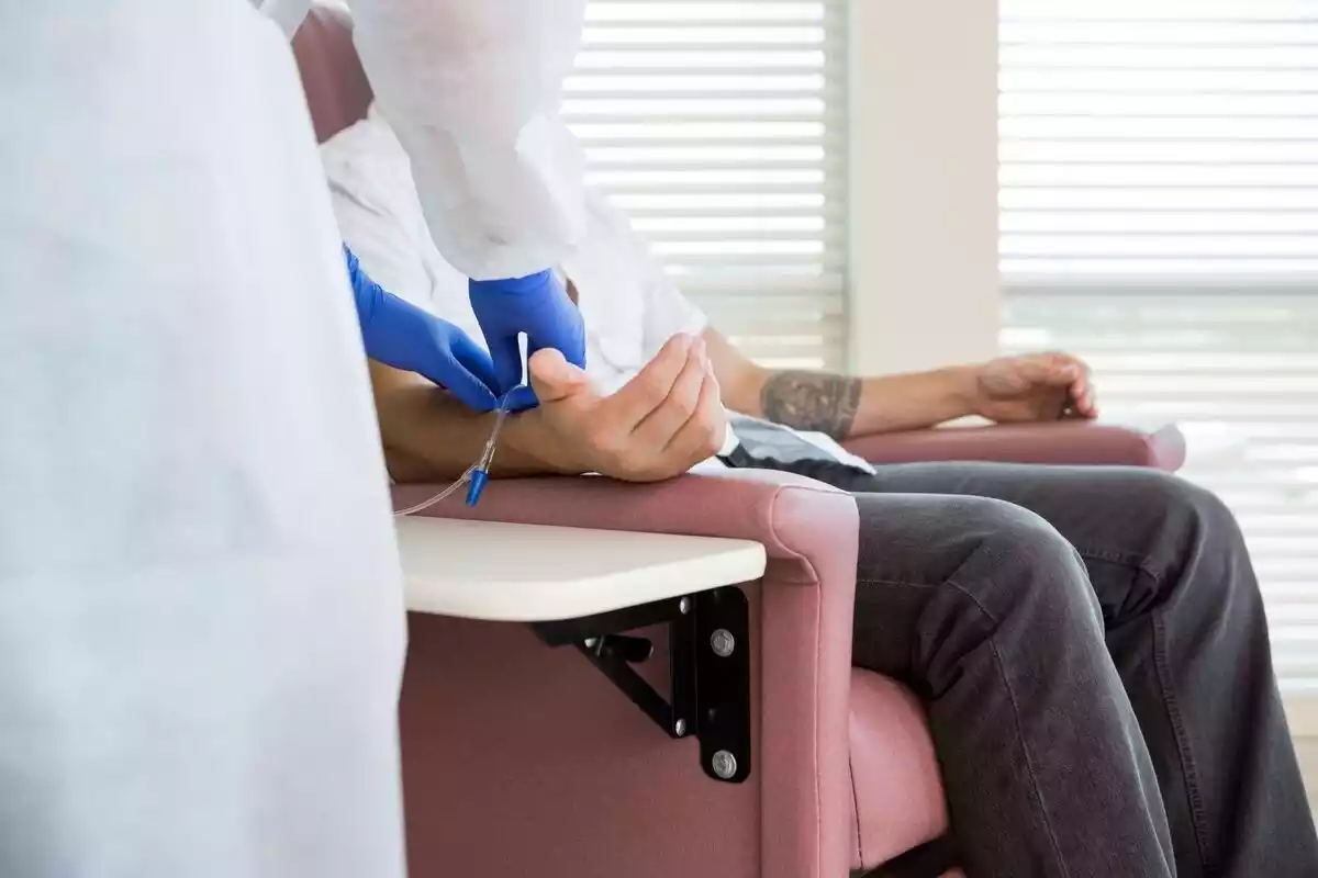 Persona sentada en una butaca recibiendo quimioterapia