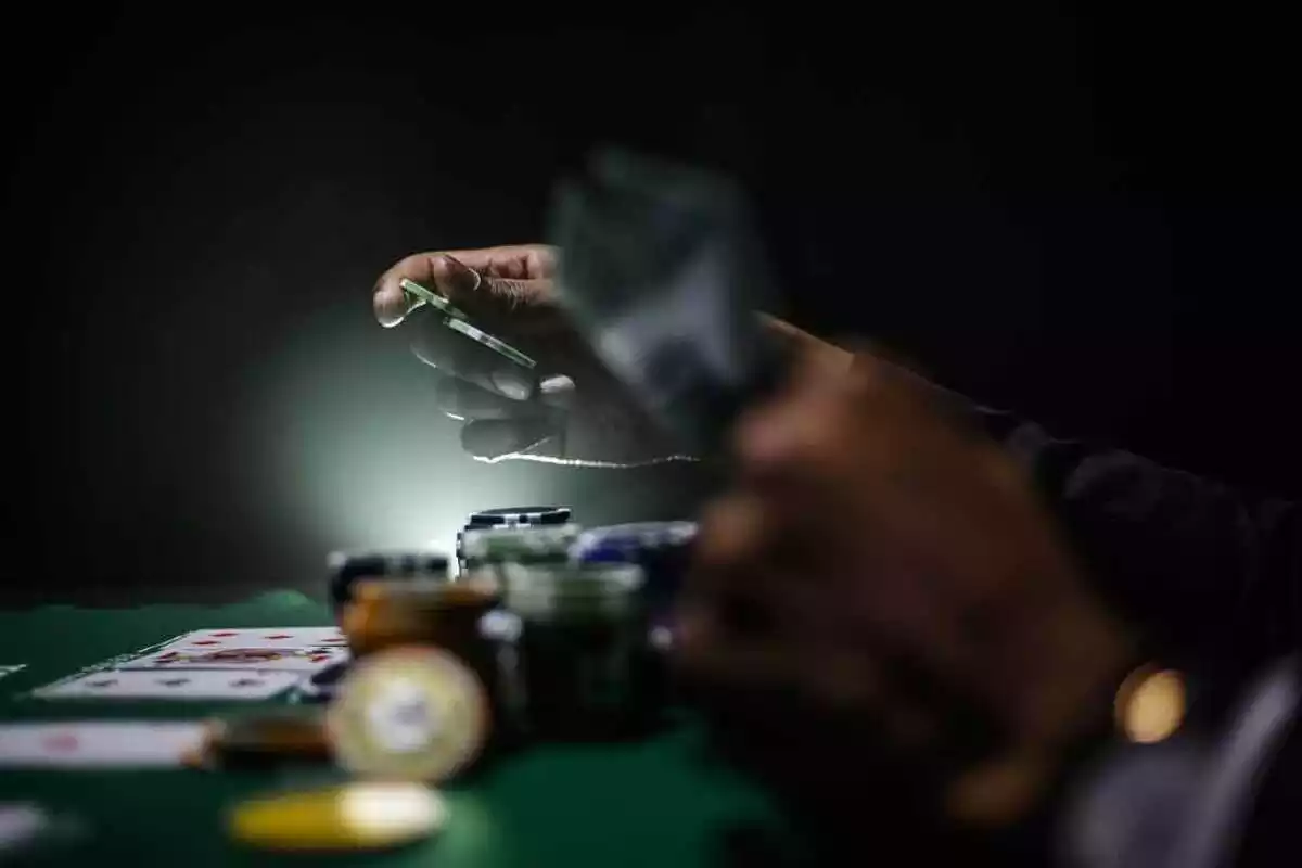 Primer plano de las manos de un croupier sosteniendo cartas y fichas de poker