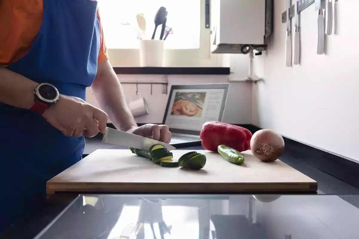 Fotografía de una persona cortando verduras en una cocina