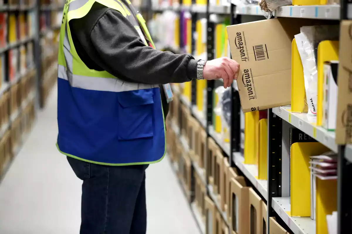 Un operario de Amazon colocando paquetes en el estante de su centro logístico