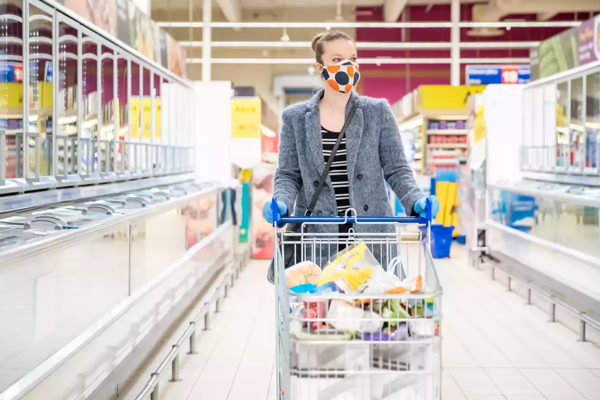 Mujer con mascarilla comprando en un supermercado