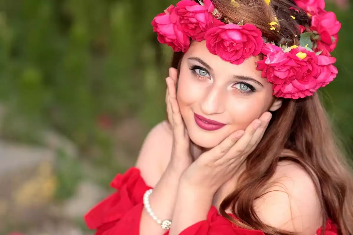 Una mujer sonriendo con una corona de flores de color rosa, a juego con su vestido