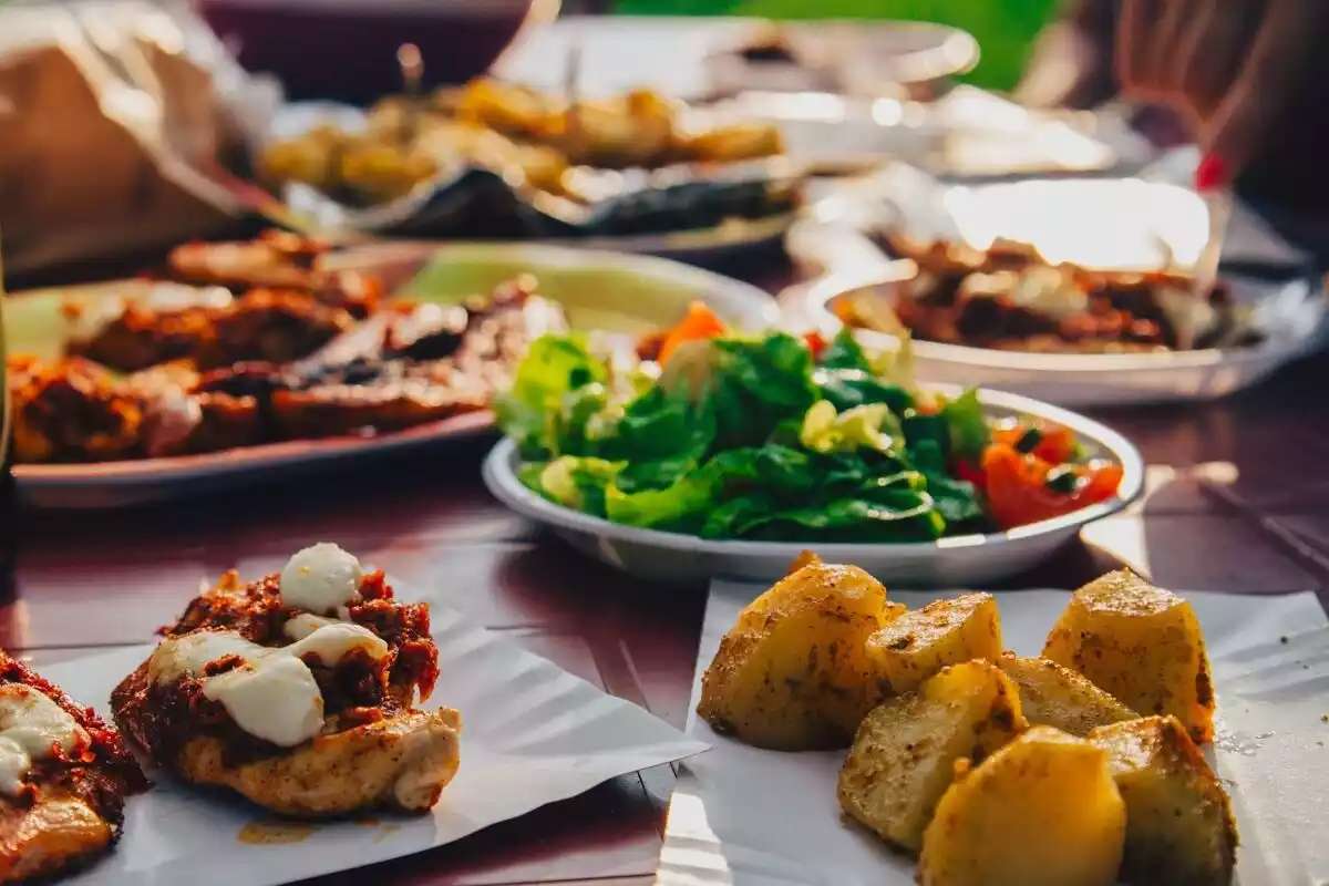 Una mesa llena de comida con platos de verdura y patatas
