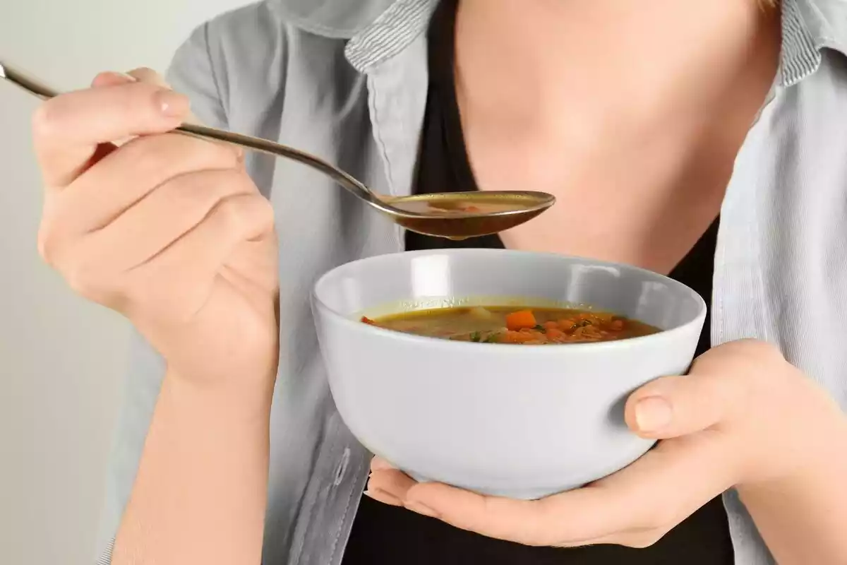 Una mujer comiendo con cuchara de un bol de comida
