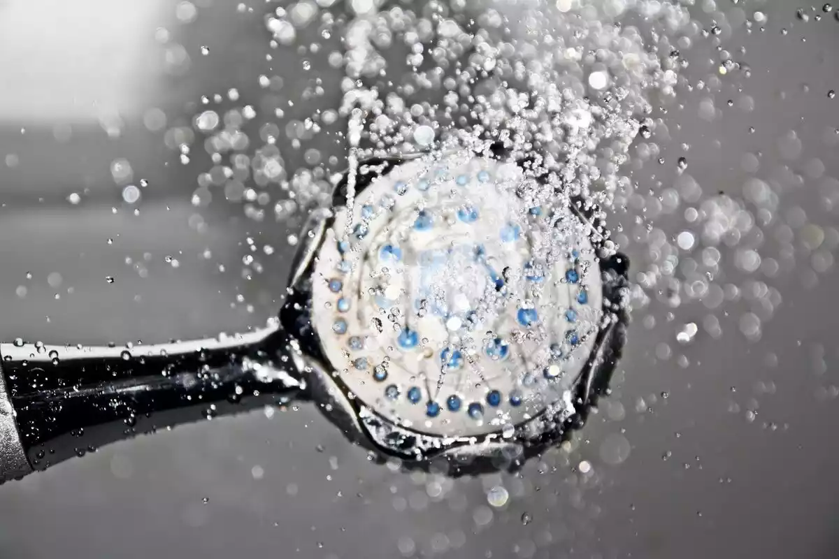 Una alcachofa de ducha con agua saliendo por los agujeritos de color azul