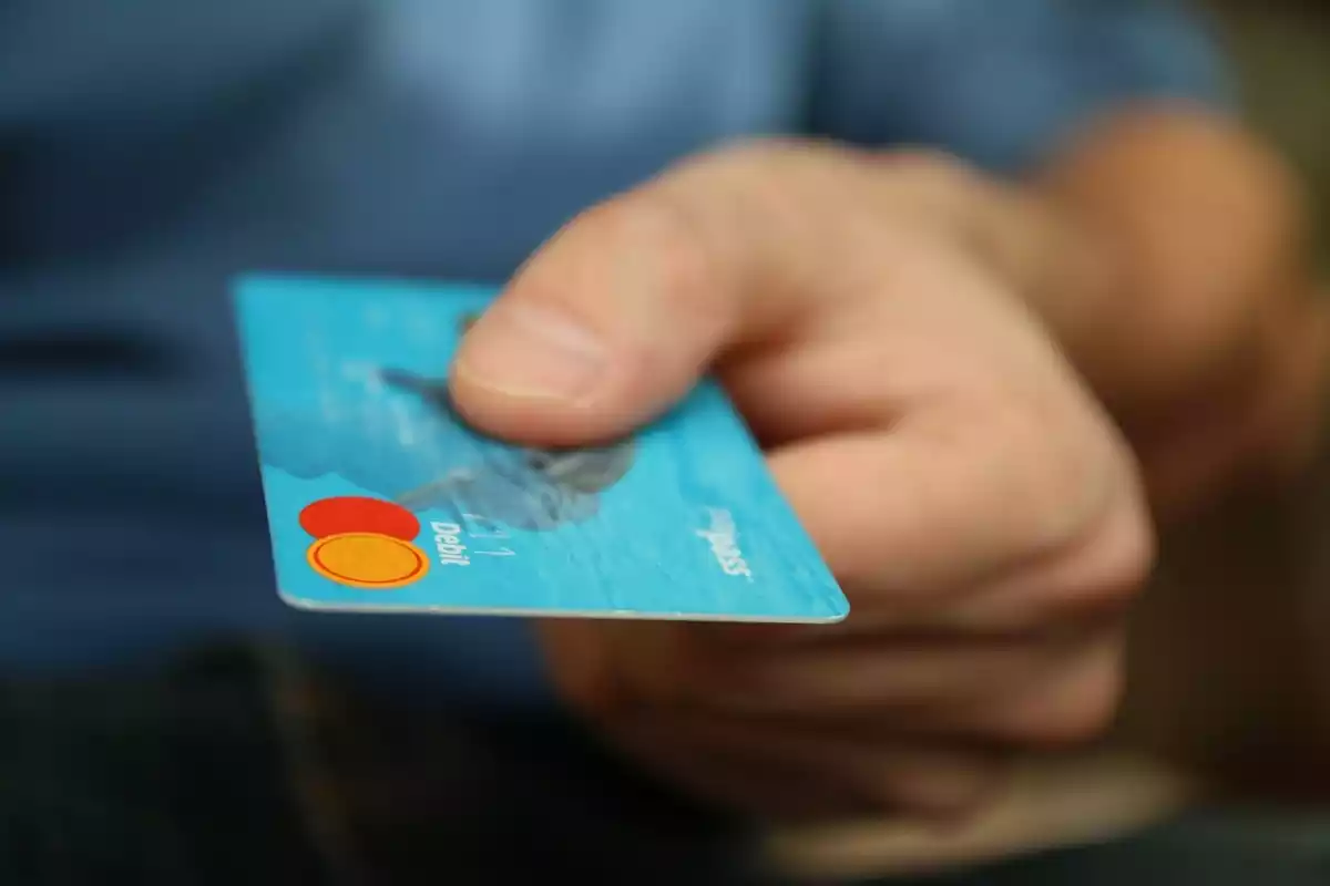 Plano detalle de la mano de una persona cogiendo la tarjeta de crédito