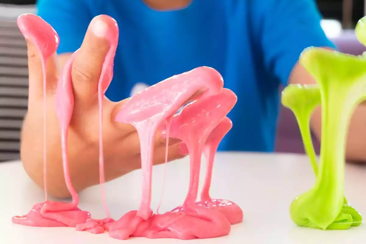 Manos de un niño con slime rosa y verde