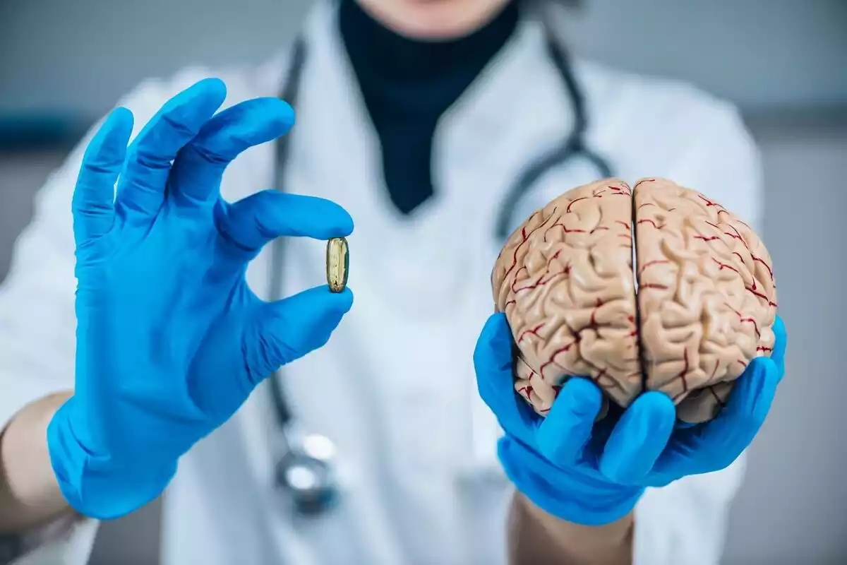 Doctor sosteniendo en una mano una pastilla y en otra un cerebro