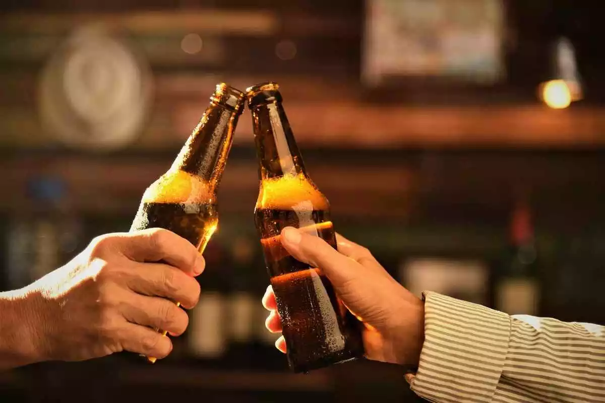 Dos manos juntando dos botellas de cerveza