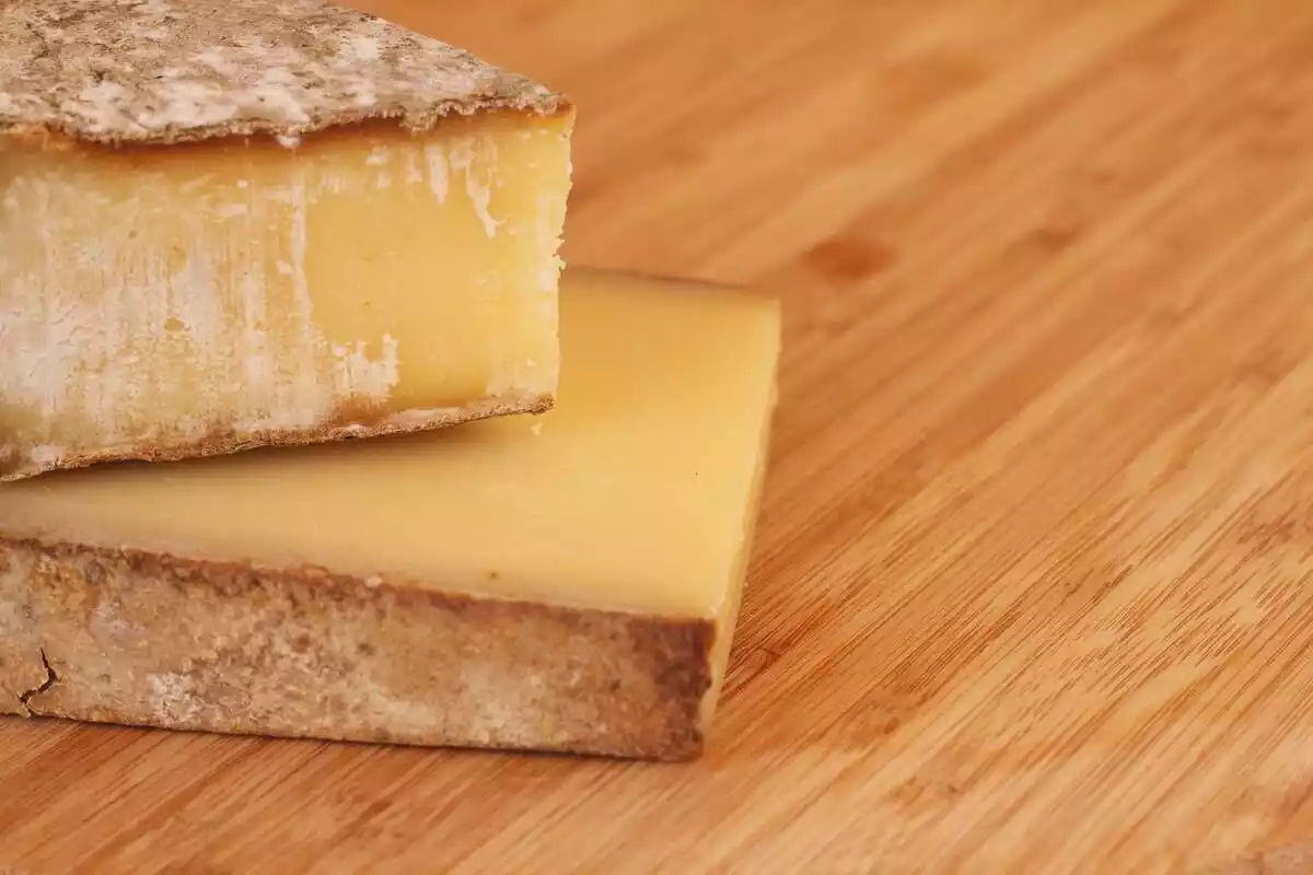 Dos piezas de queso encima de una mesa de madera