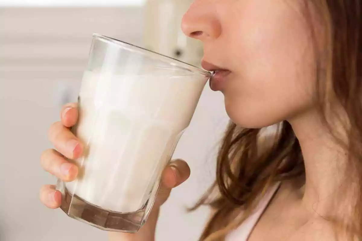 Mujer bebe leche de un vaso
