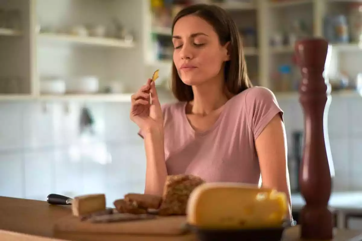 Mujer sentada comiendo un trozo de queso