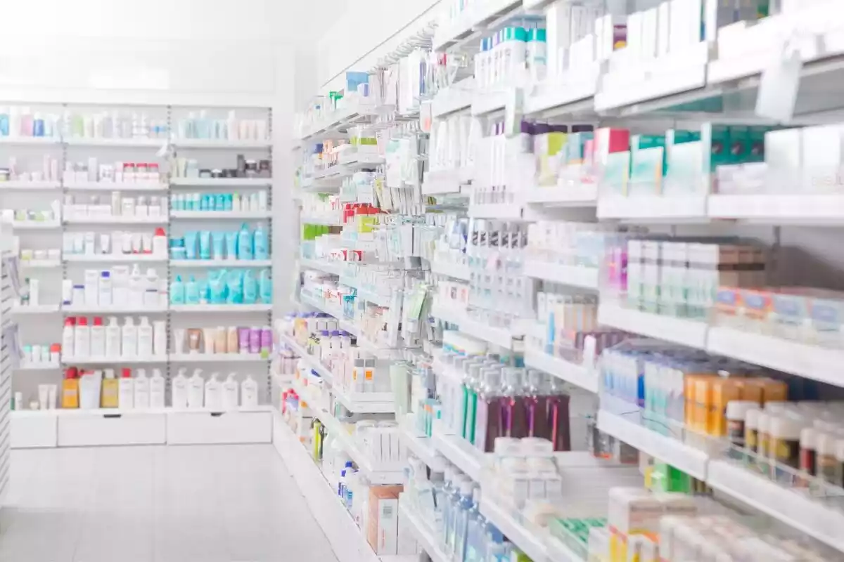 Pasillo de una farmacia con las estanterías llenas de medicamentos