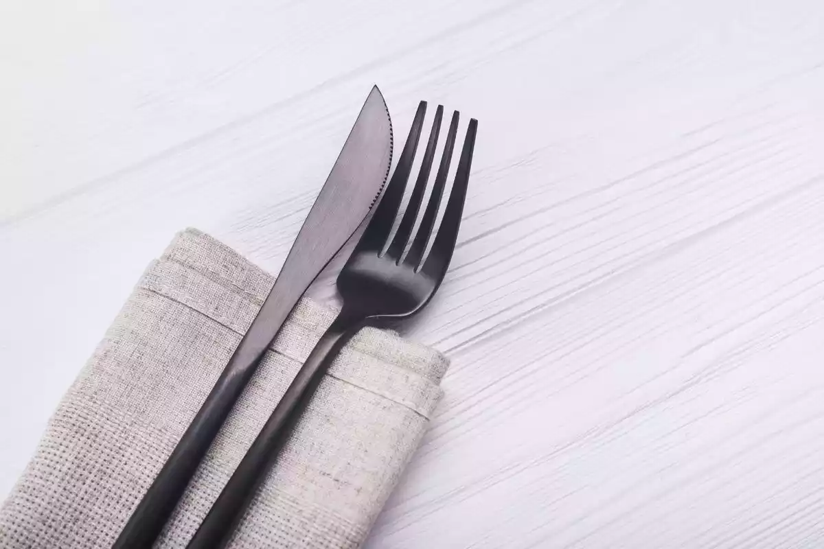 Un tenedor y un cuchillo sobre una servilleta de color gris