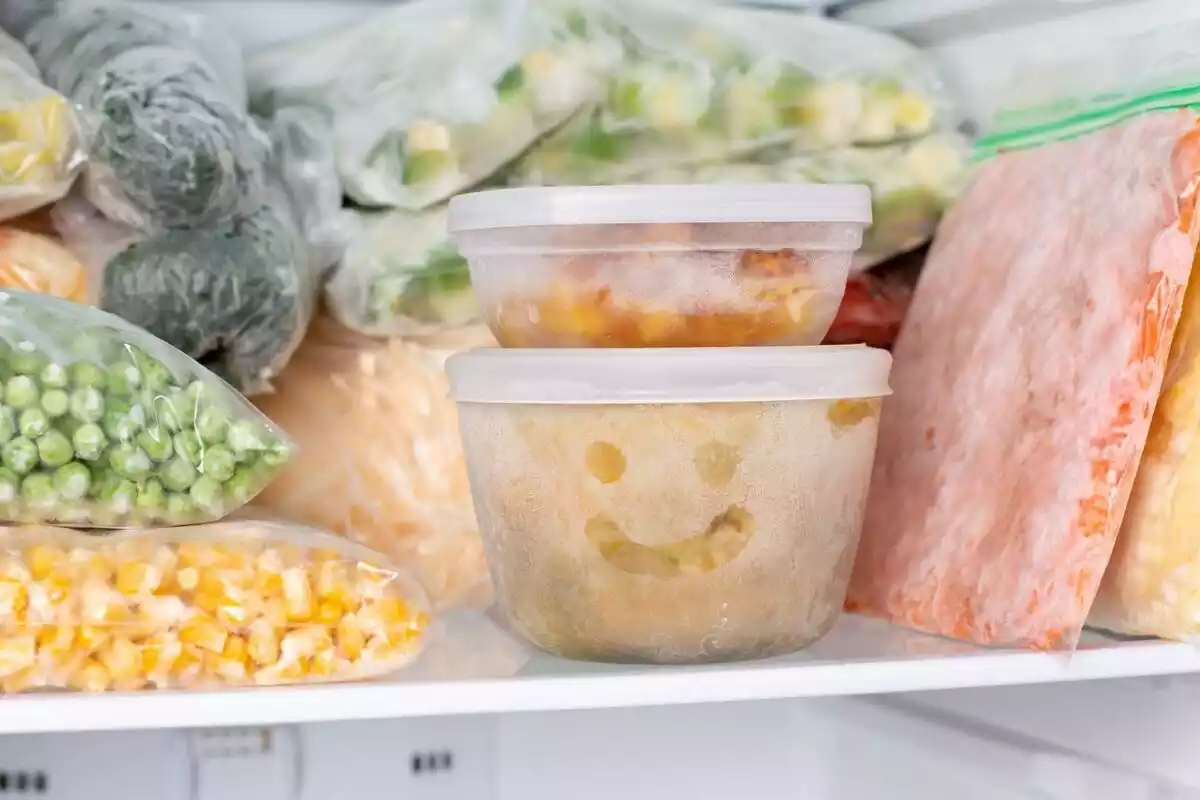 Varios envases y bolsas con verdura y carne en un congelador