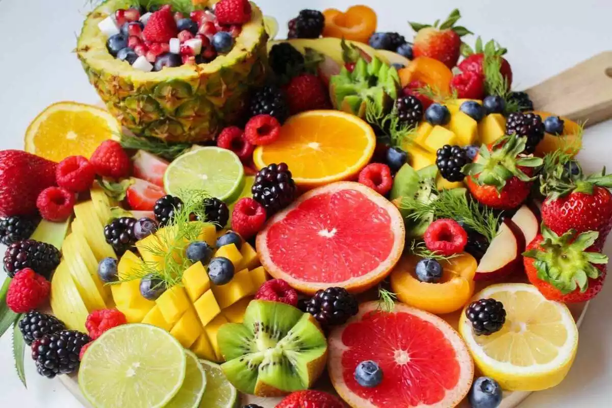 Limones, kiwis, mango, piña, fresas y otras frutas encima de una mesa