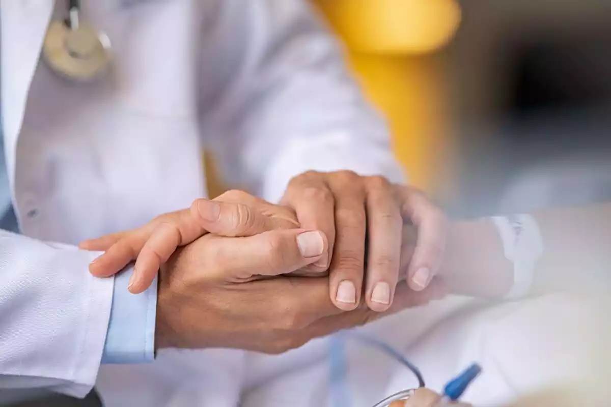 Doctor sosteniéndole la mano a un paciente