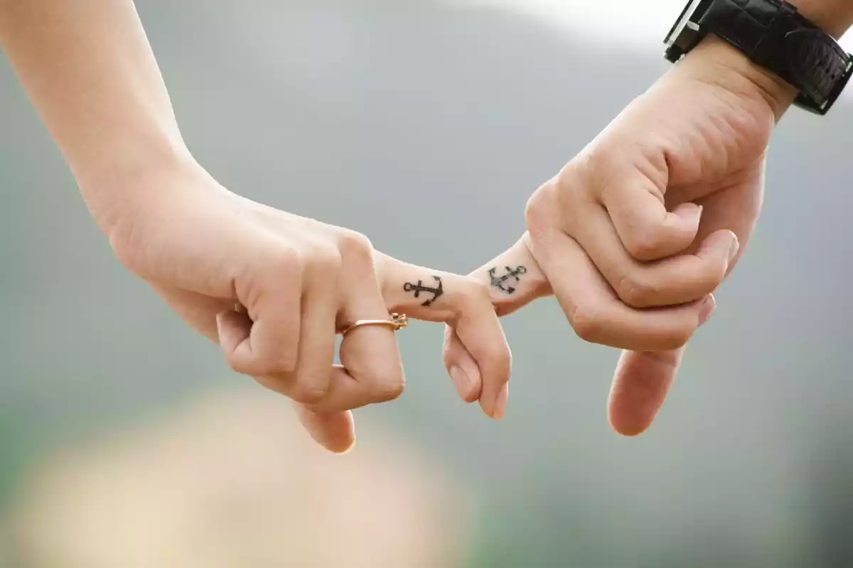 Dos manos sostenidas con un tatuaje cada uno