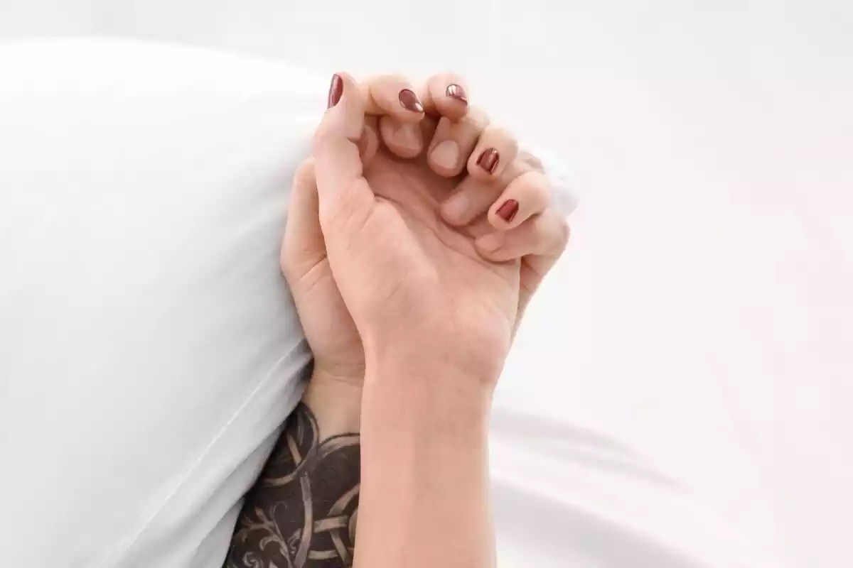 Dos manos sostenidas encima de una almohada