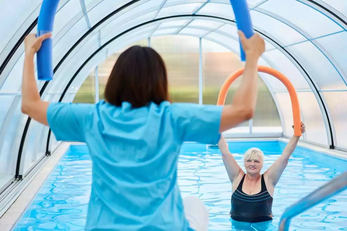 Entrenadora y alumna practicando aquagym en una piscina