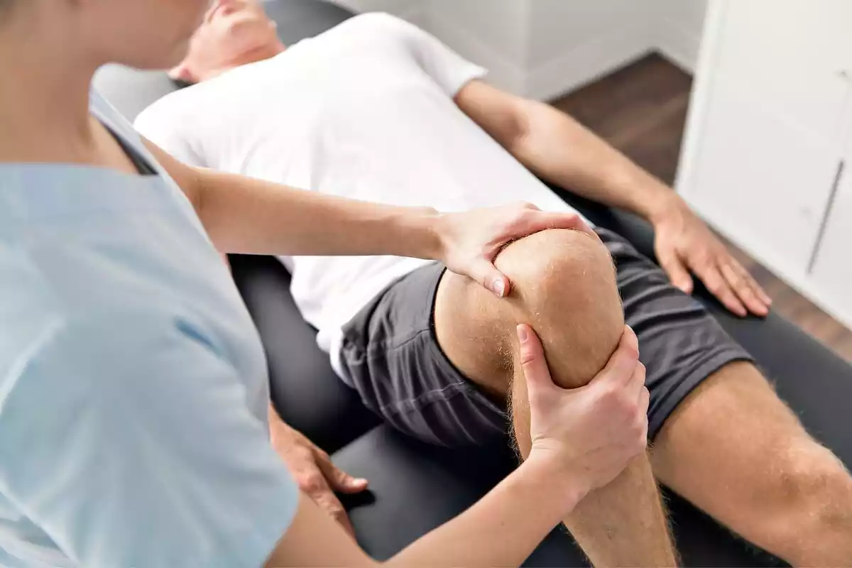 Fisioterapeuta masajeando la rodilla de un hombre