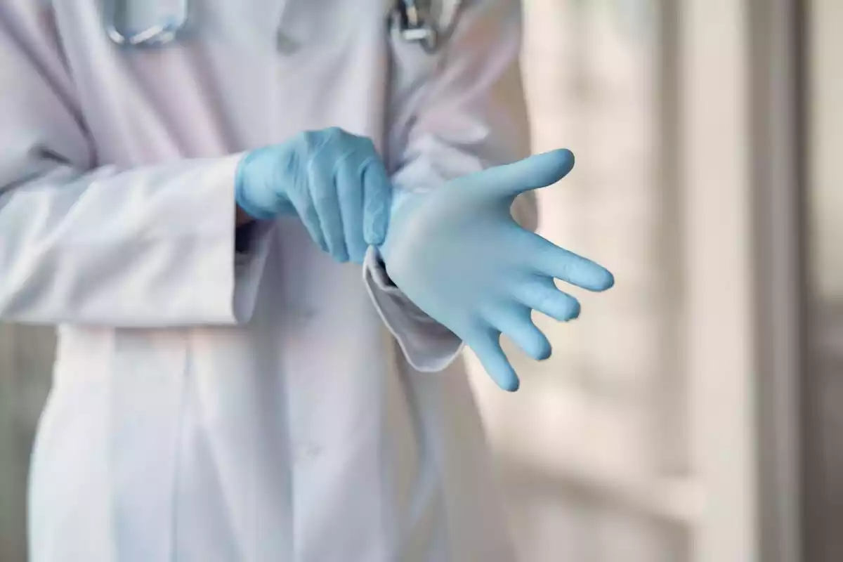 Médico poniéndose bien un guante azul en la mano