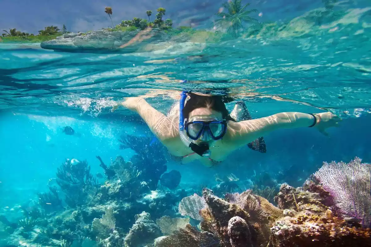 Mujer con gafas y tubo acuático practicando snorkel
