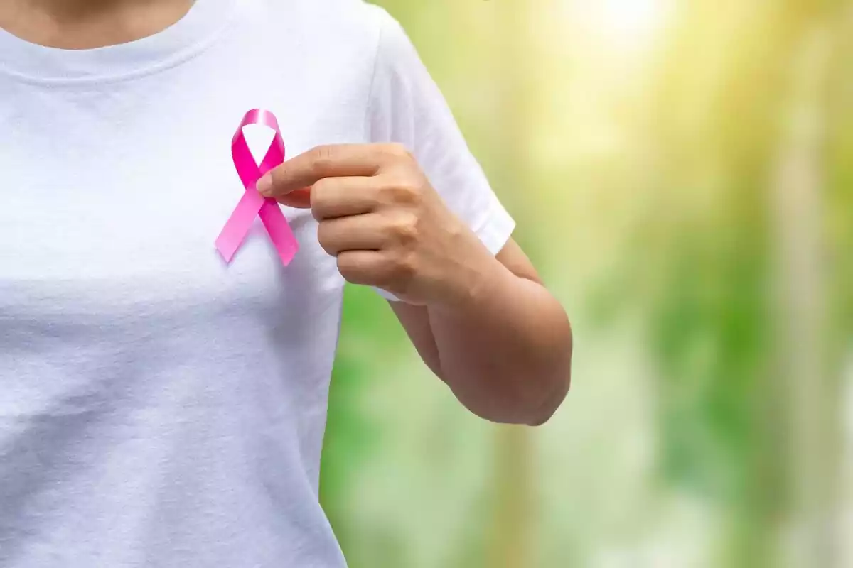 Mujer sosteniendo un lazo que representa el apoyo al cáncer de mama