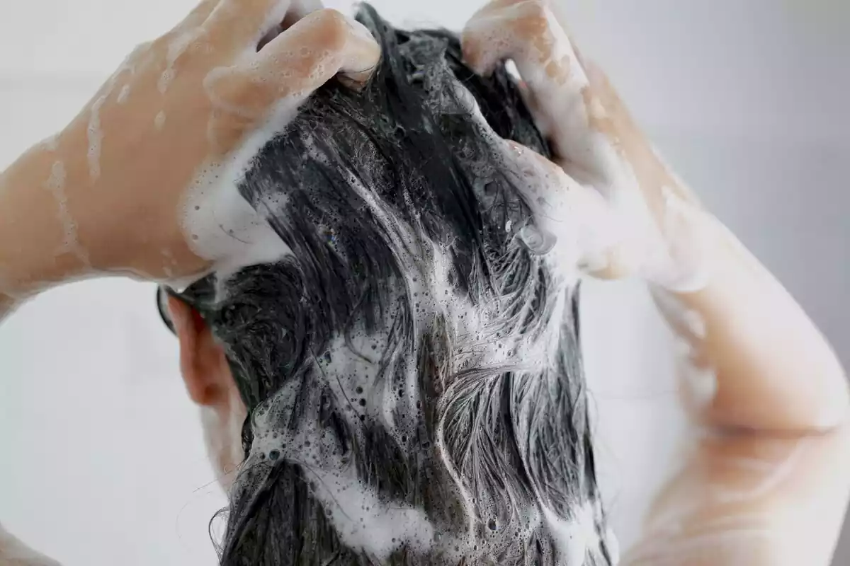 Persona lavándose el pelo con champú