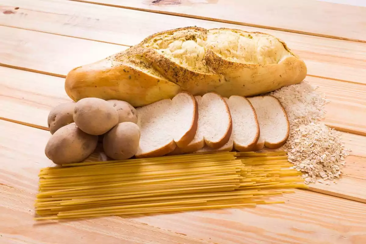 Una barra y rebanas de pan junto a patatas y pasta