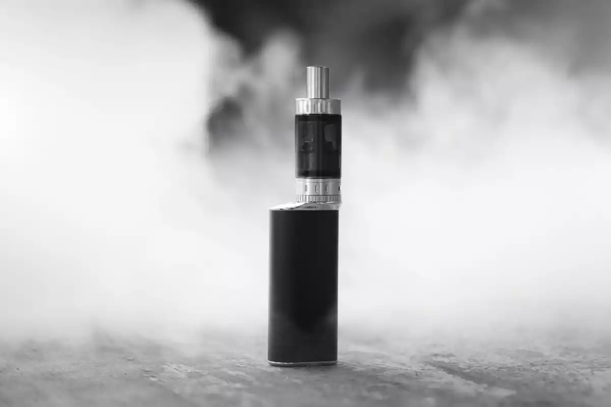 Vaporizador de color negro rodeado de humo