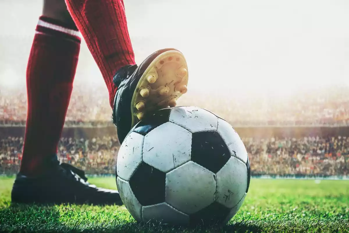Balón de fútbol sujeto por un pie en un campo de fútbol