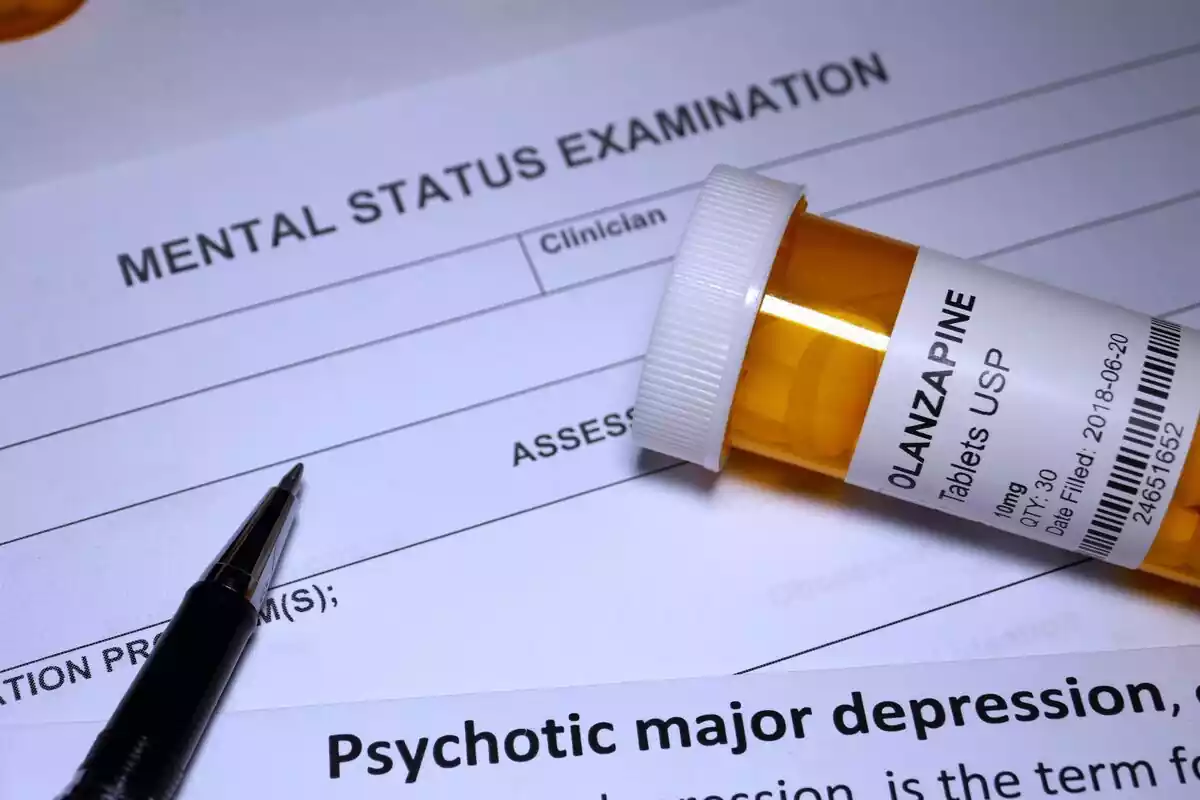 Bote de pastillas encima de un examen de salud mental