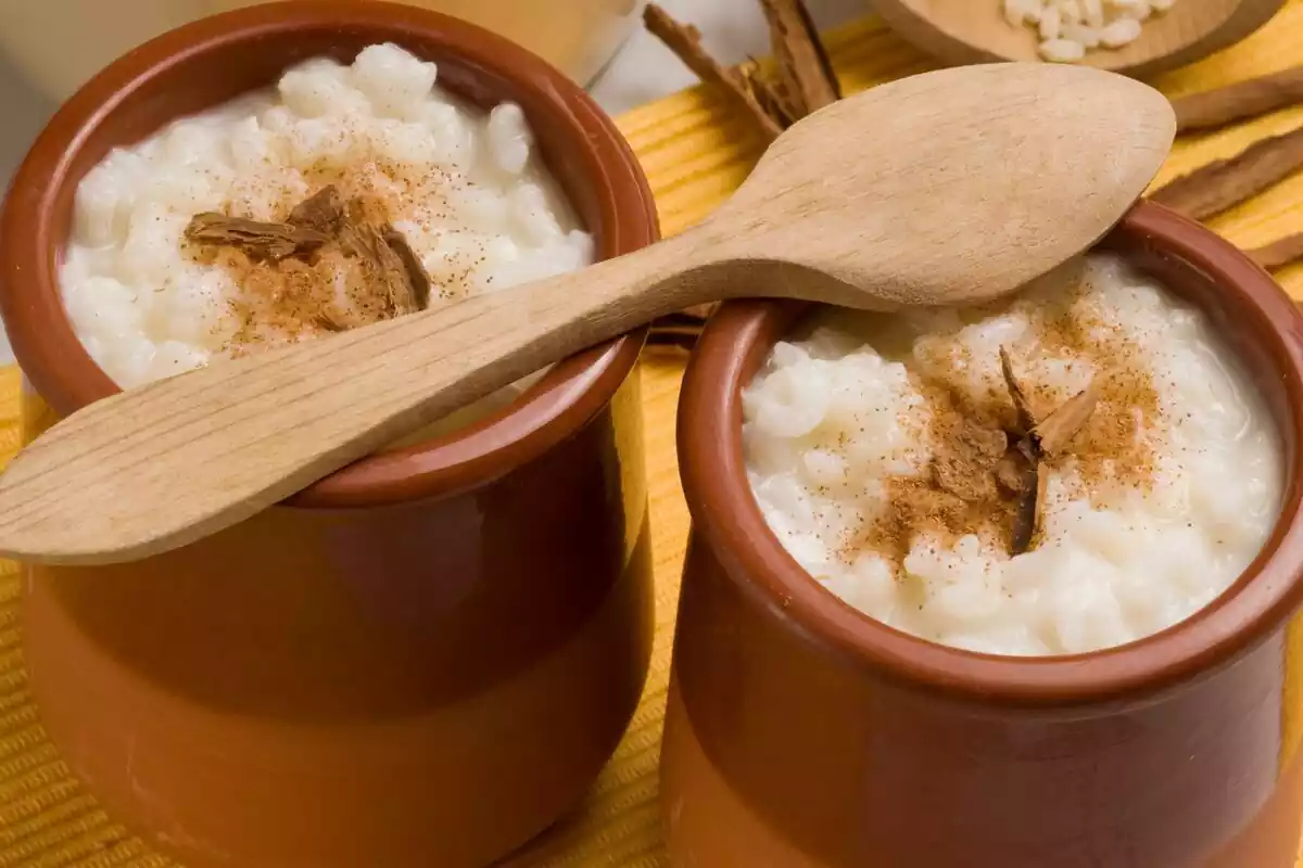 Dos vasos de cerámica con arroz con leche y una cuchara encima