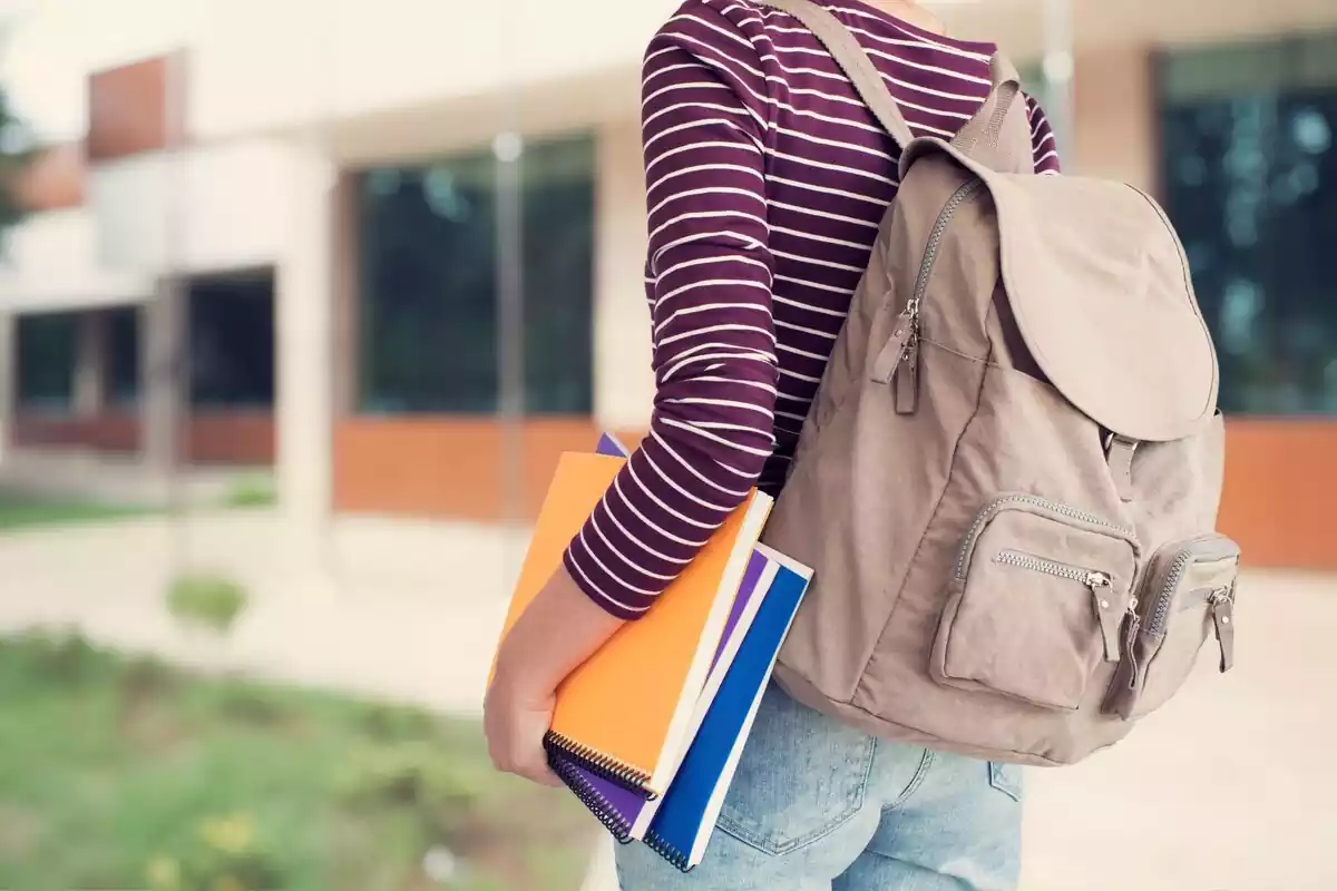 Estudiante con mochila sosteniendo unas libretas