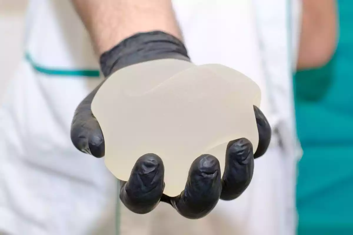 Implante mamario en una mano con un guante