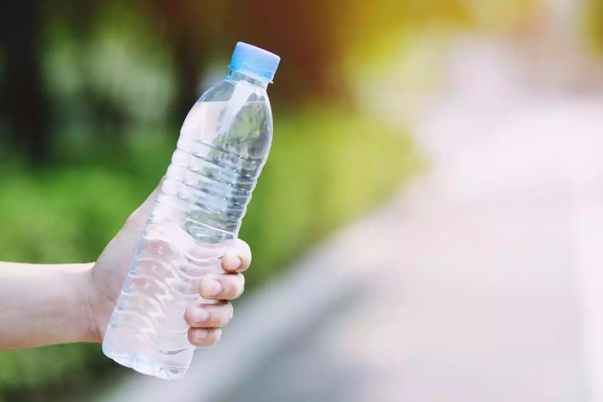 Mano sosteniendo una botella de agua de plástico