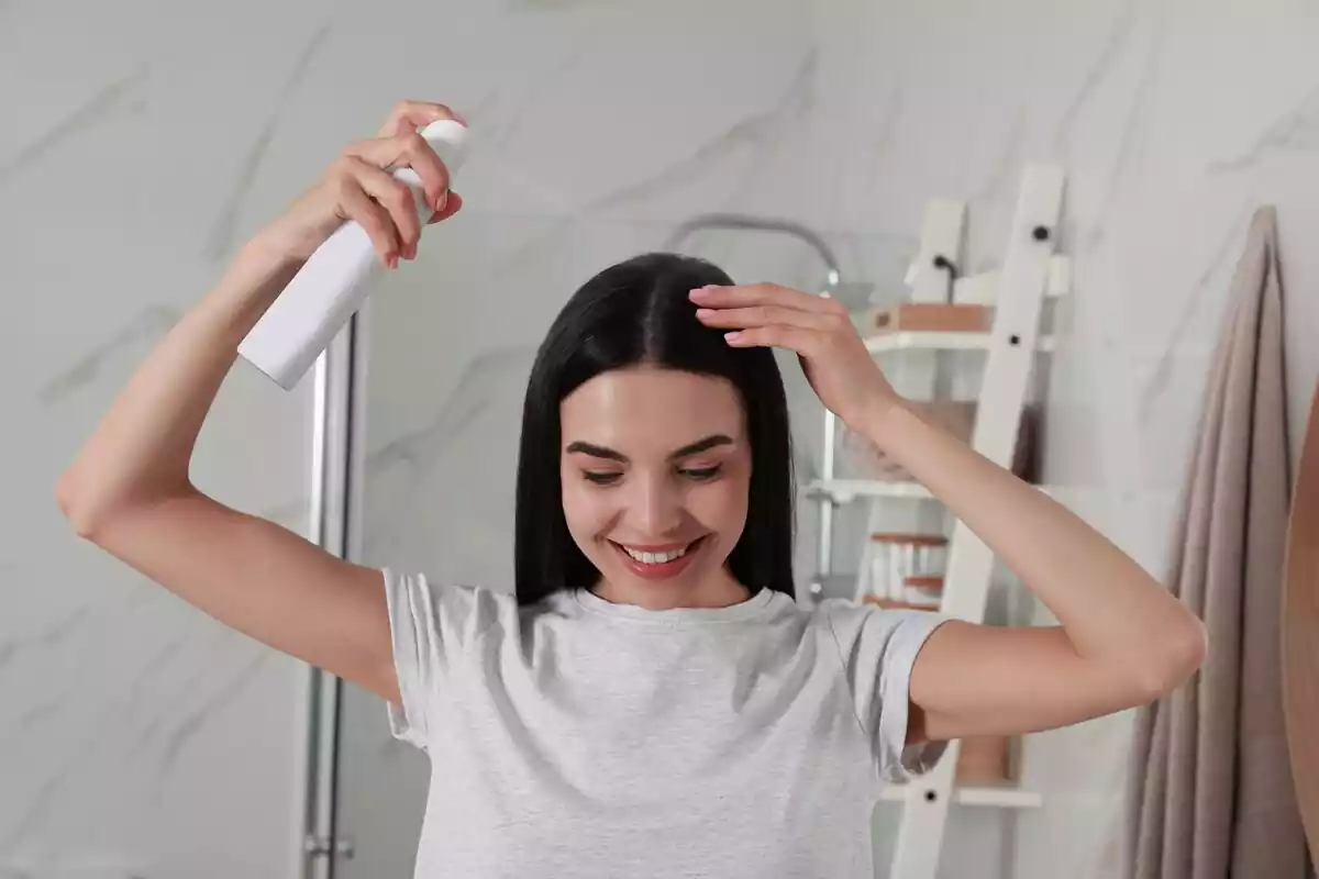 Mujer aplicándose champú en seco sobre el pelo