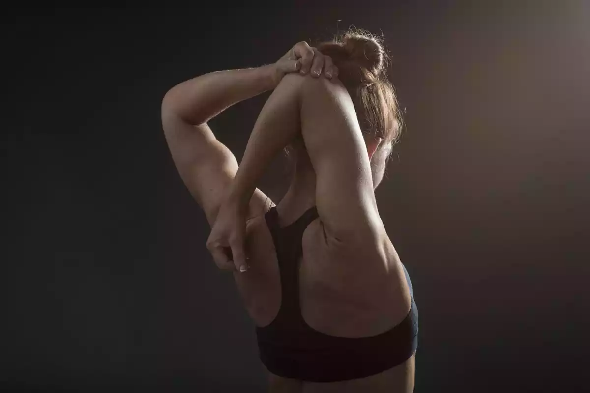 Mujer de espaldas haciendo estiramientos musculares de brazo