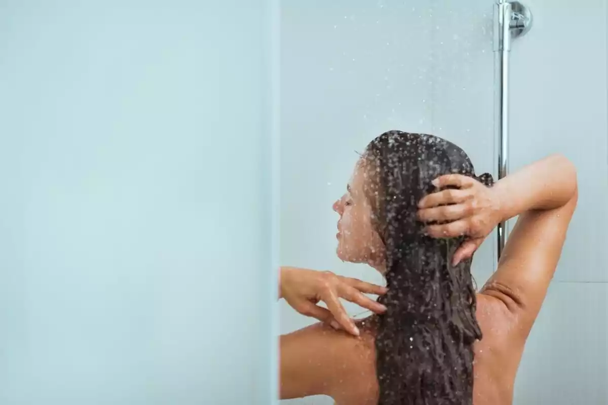 Mujer de espaldas lavándose el pelo