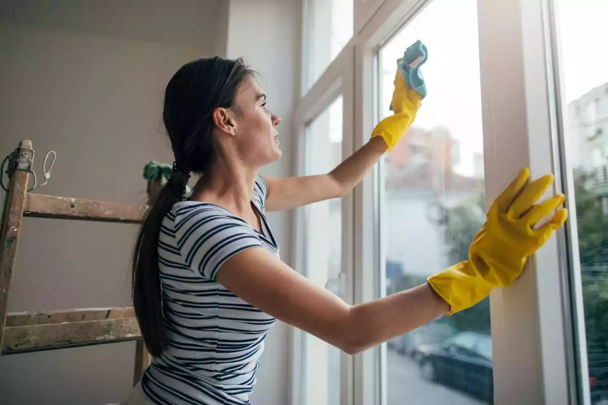 Mujer limpiando el cristal de una ventana con una bayeta