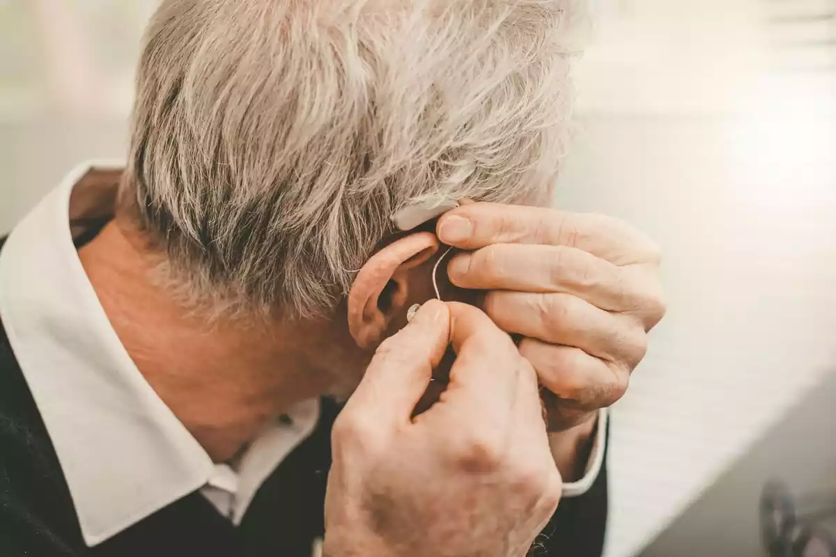 Persona colocándose un audífono en la oreja