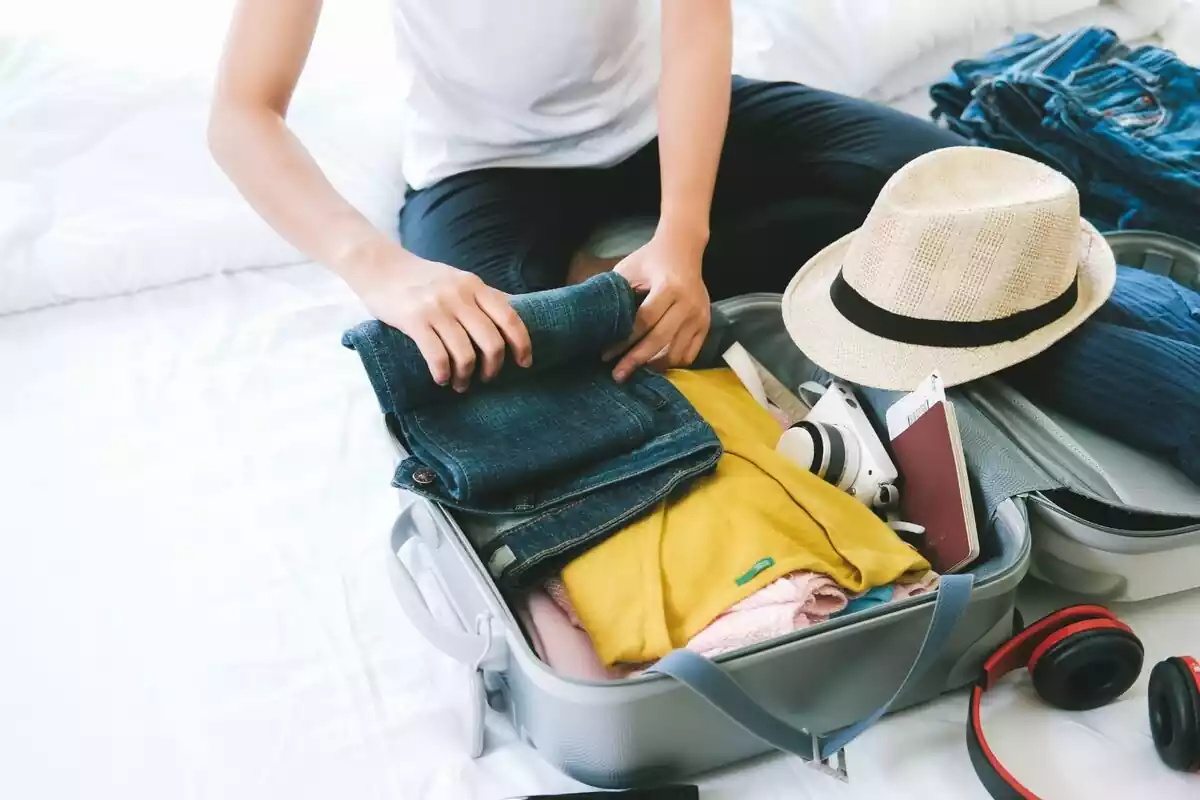 Persona metiendo en una maleta de viaje ropa y complementos