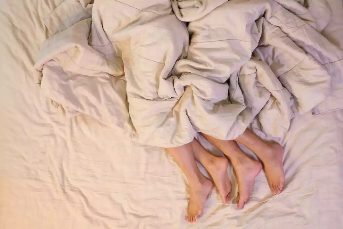 Plano de los pies de una pareja tumbados en una cama