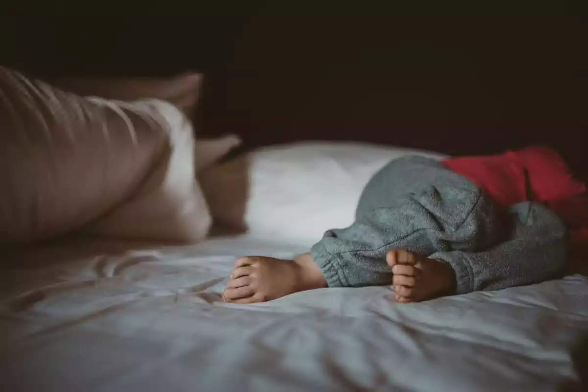Un niño durmiendo en la cama con los pies a la vista