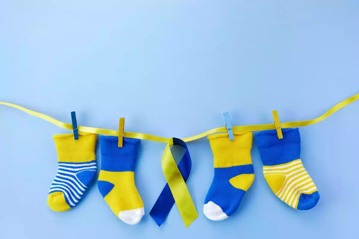 Una cuerda amarilla donde hay colgados cuatro calcetines y un lazo