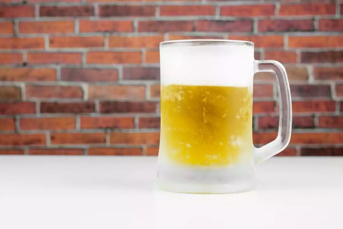 Una jarra helada llena de cerveza con fondo de ladrillos